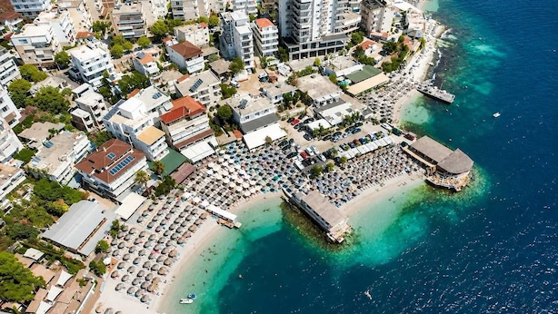Oversigtsbillede af et kystområde med en strand, en lysthavn og boligbygninger.