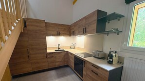 A modern kitchen with wooden cabinets, a sink, a toaster, and a window with a view. - REFLETS D'ARDENT 101  By Avecoeur (Montriond)