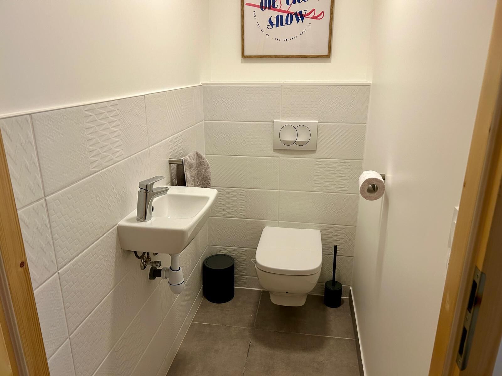 A small bathroom with a sink, toilet, and a trash can.