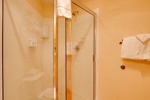 Eine gläserne Dusche mit einem weißen Handtuch an der Wand, einer Seifenspender und einem kleinen Handtuchhalter.