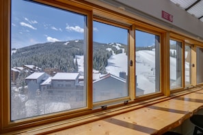 Eine Reihe großer Fenster mit Holzrahmen, die einen Blick auf eine verschneite Berglandschaft freigeben.