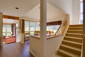 Una habitación amplia con una escalera, ventanas grandes y vistas al exterior.