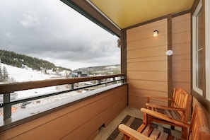 Ein Balkon mit Holellentrailung, einem Holzstuhl und Blick auf eine verschneite Landschaft.