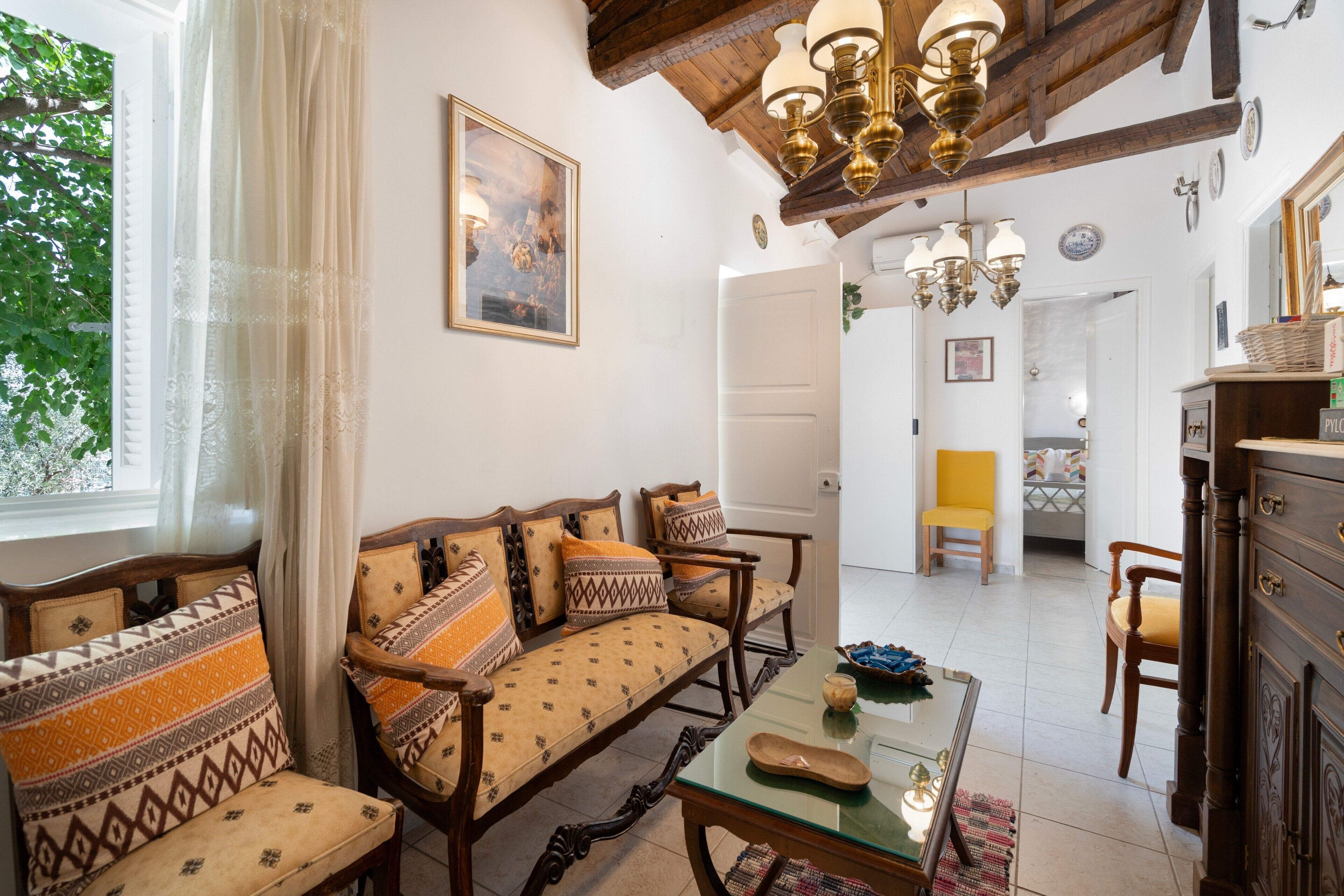 A traditional room with a sofa set, a dining table, and a chandelier.