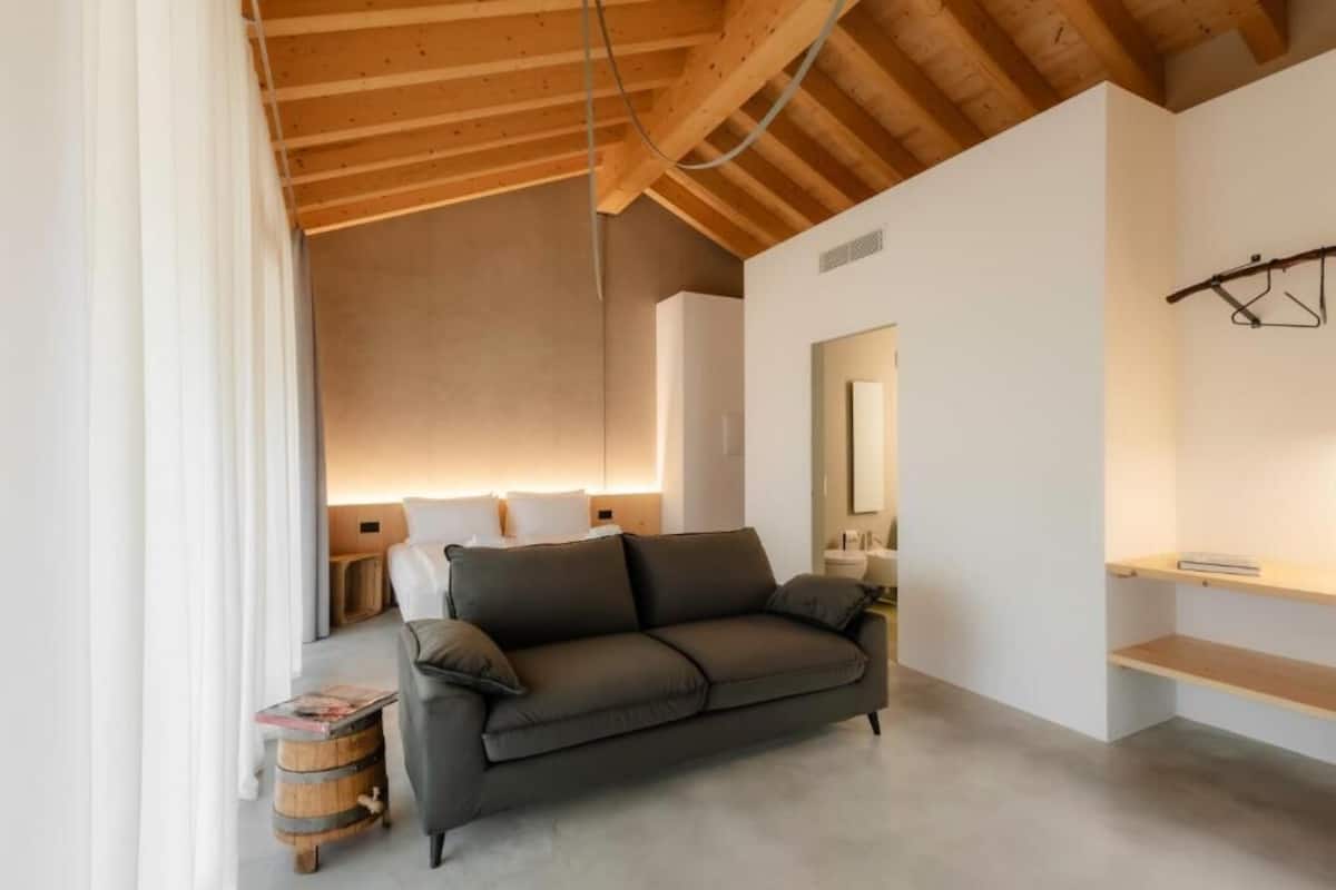 A modern room with a sofa, a wooden ceiling, a mirror, and a small table.