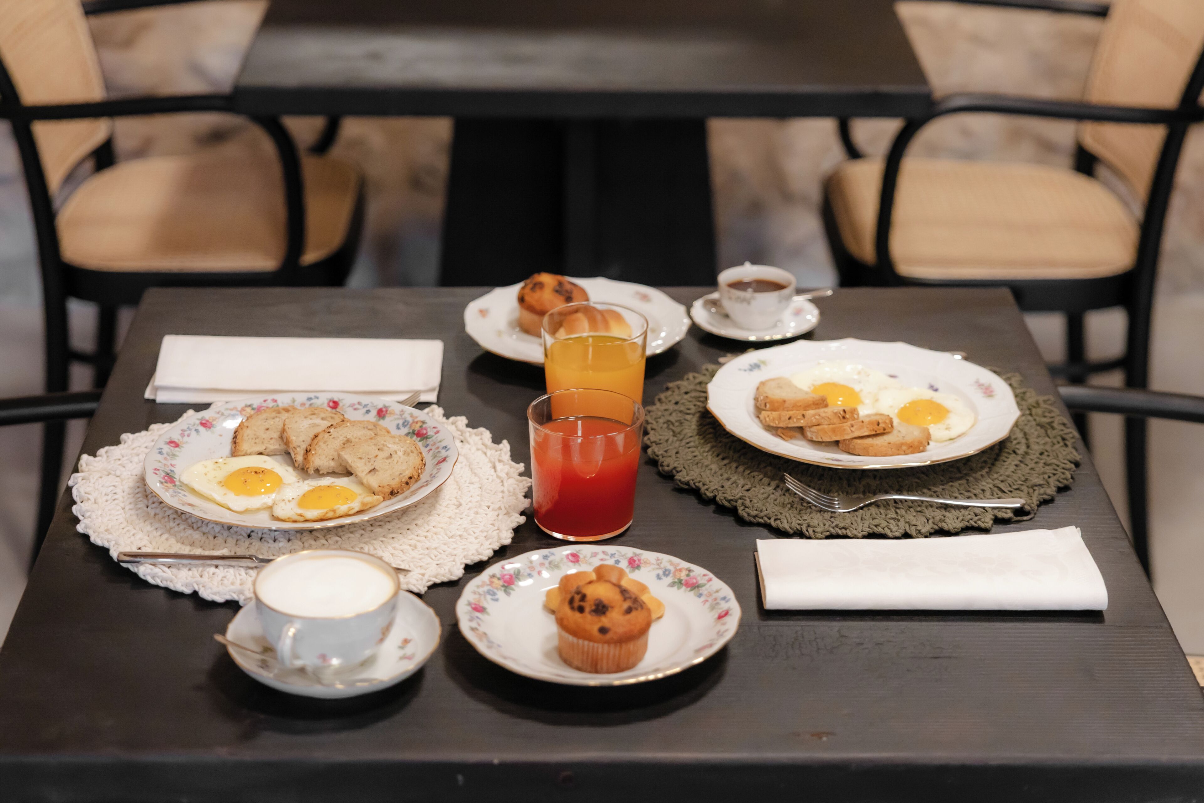 Una mesa dispuesta para el desayuno, con huevos, muffins y un vaso de jugo.