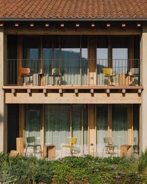 Ein zweistöckiges Gebäude mit Balkon, großen Fenstern und Außenbestuhlung.
