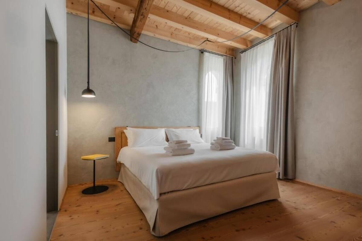 Ein Schlafzimmer mit Holzboden, einem Bett mit weißen Leinentüchern, einem kleinen Tisch und einer Hängelampe.