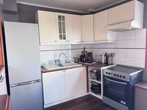 Une cuisine de taille réduite avec des meubles blancs, une cuisinière en acier inoxydable et un réfrigérateur blanc.