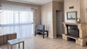 Un salon avec une cheminée, un téléviseur et une fenêtre avec des rideaux.