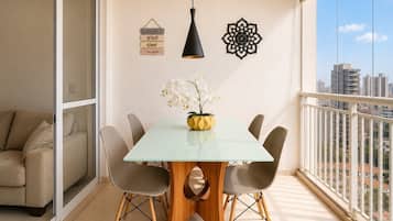A balcony with a dining area, a sofa, a hanging light, and decorative wall art.