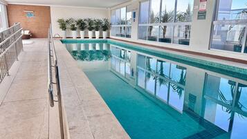 Una piscina al aire libre, sillones reclinables de piscina