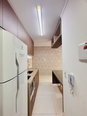 A modern kitchen with a refrigerator, oven, and a small dining area.