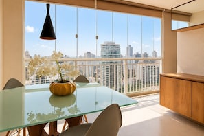 Un comedor moderno con una mesa de vidrio, sillas y un jarrón con flores.