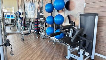 Un gimnasio con equipo de ejercicio, una pared con un cartel y suelo de madera.