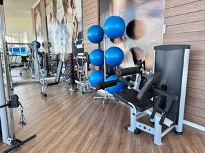 Un gimnasio con equipo de ejercicio, una pared con un cartel y suelo de madera.