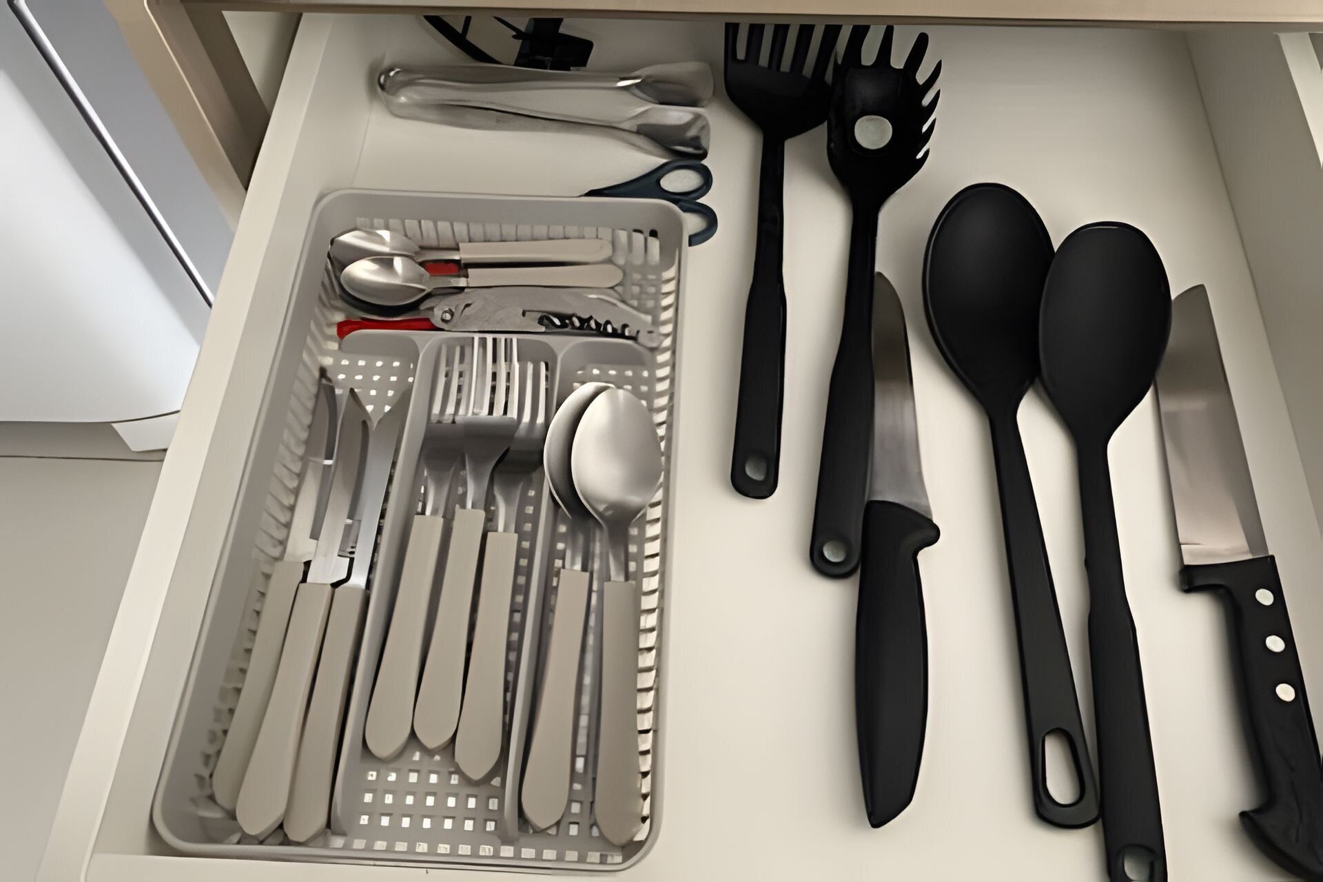Uma gaveta com utensílios de cozinha bem organizados, incluindo colheres, garfos, facas e espátulas.