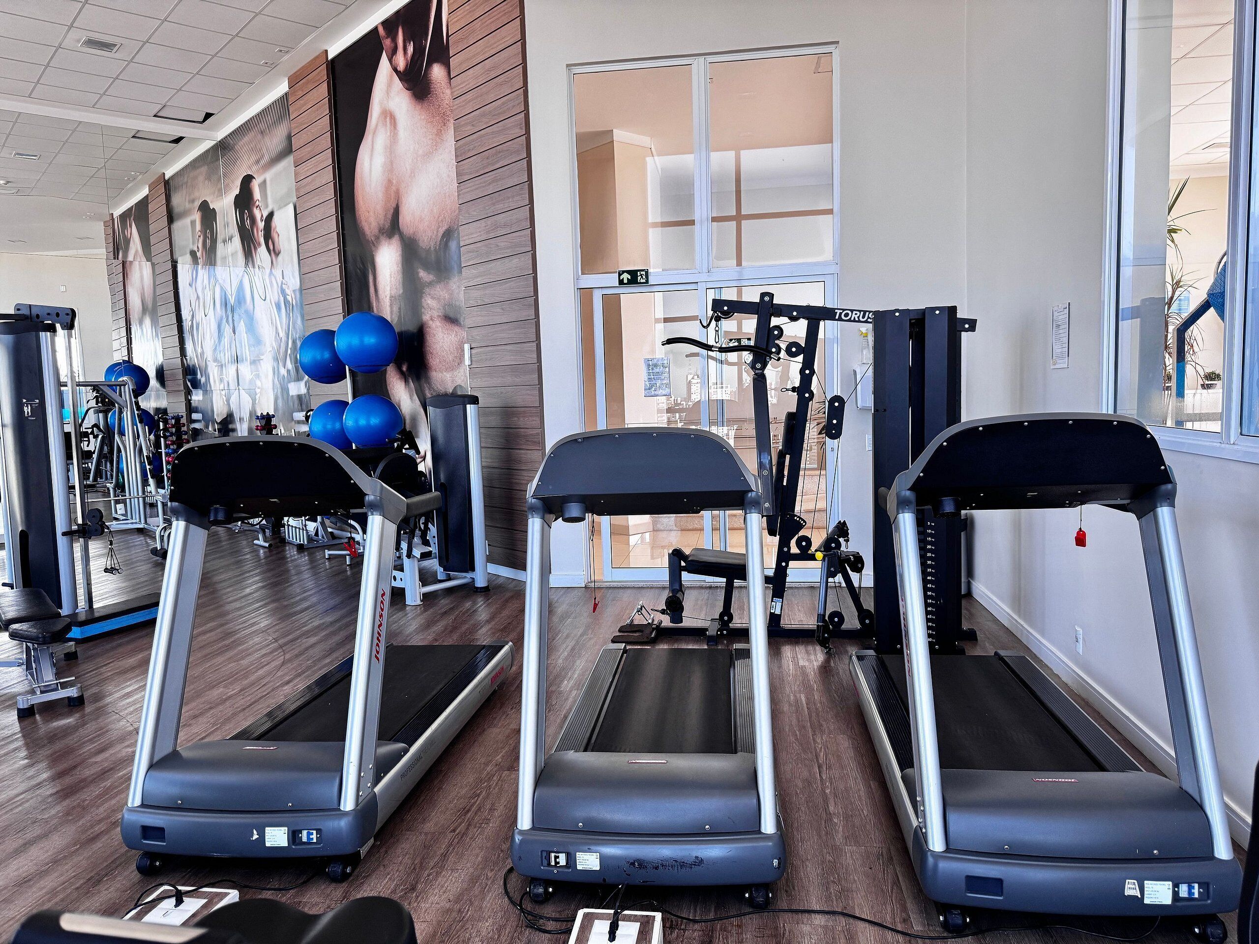 A gym with treadmills, weight machines, and exercise balls.