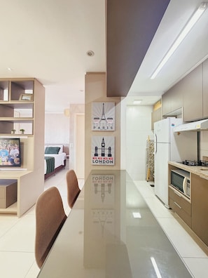 Una cocina moderna con comedor, que incluye un televisor de pantalla plana, un refrigerador y un microondas.