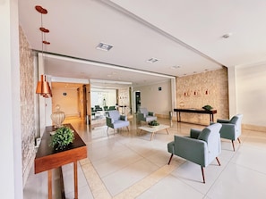 Un moderno vestíbulo de hotel con mostrador de recepción, zona de estar y una pared con textura.