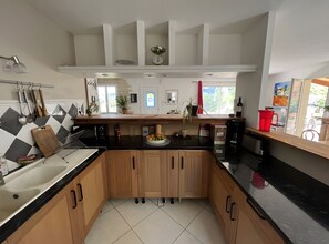 A modern kitchen with a central island, wooden cabinets, and a black countertop.