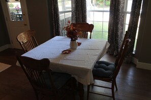 A dining area with a table covered by a white tablecloth, surrounded by wooden chairs with cushioned seats. - Peaceful 4-bedroom house with AC in lovely Loveland (Loveland)