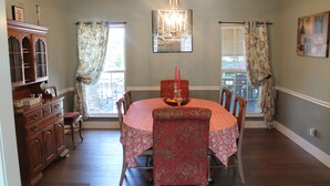 A dining room with a round table, chairs, a chandelier, and a cabinet.