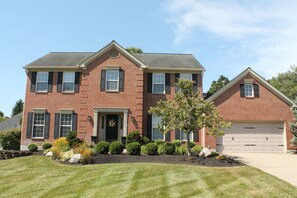 A two-story brick house with a front porch, a garage, and a well-maintained lawn. - Peaceful 4-bedroom house with AC in lovely Loveland (Loveland)