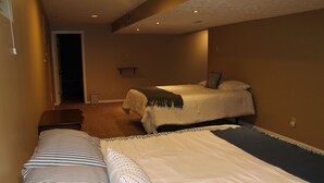 A hotel room with two beds, a hallway, and a door leading to another room.