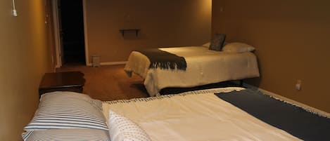 A hotel room with two beds, a hallway, and a door leading to another room.