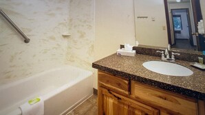 Ein Badezimmer mit einer Badewanne, einem Waschtisch, einem Spiegel und einem Handtuchhalter.