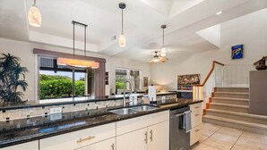 A modern kitchen with a large island, pendant lights, and a view of greenery outside. - Mauna Lani Townhome w/ Golf Course Views Beach Club Access (Kamuela)