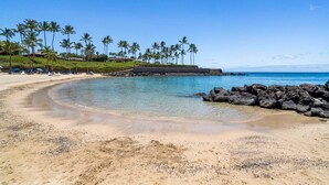 A beach with clear water, palm trees, and a rocky shoreline. - Mauna Lani Townhome w/ Golf Course Views Beach Club Access (Kamuela)