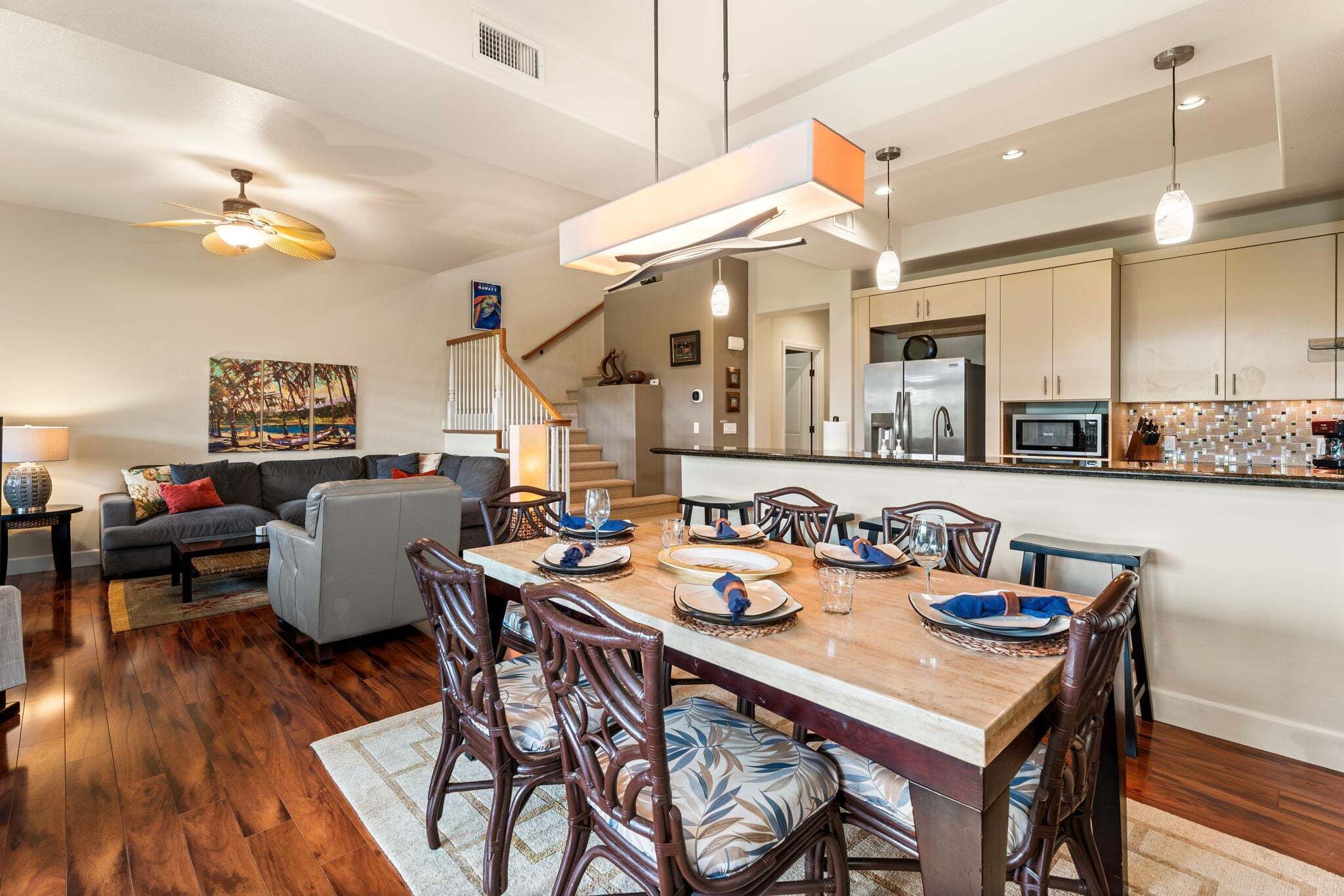 A modern kitchen with a dining area, wooden flooring, and a staircase leading to an upper level.