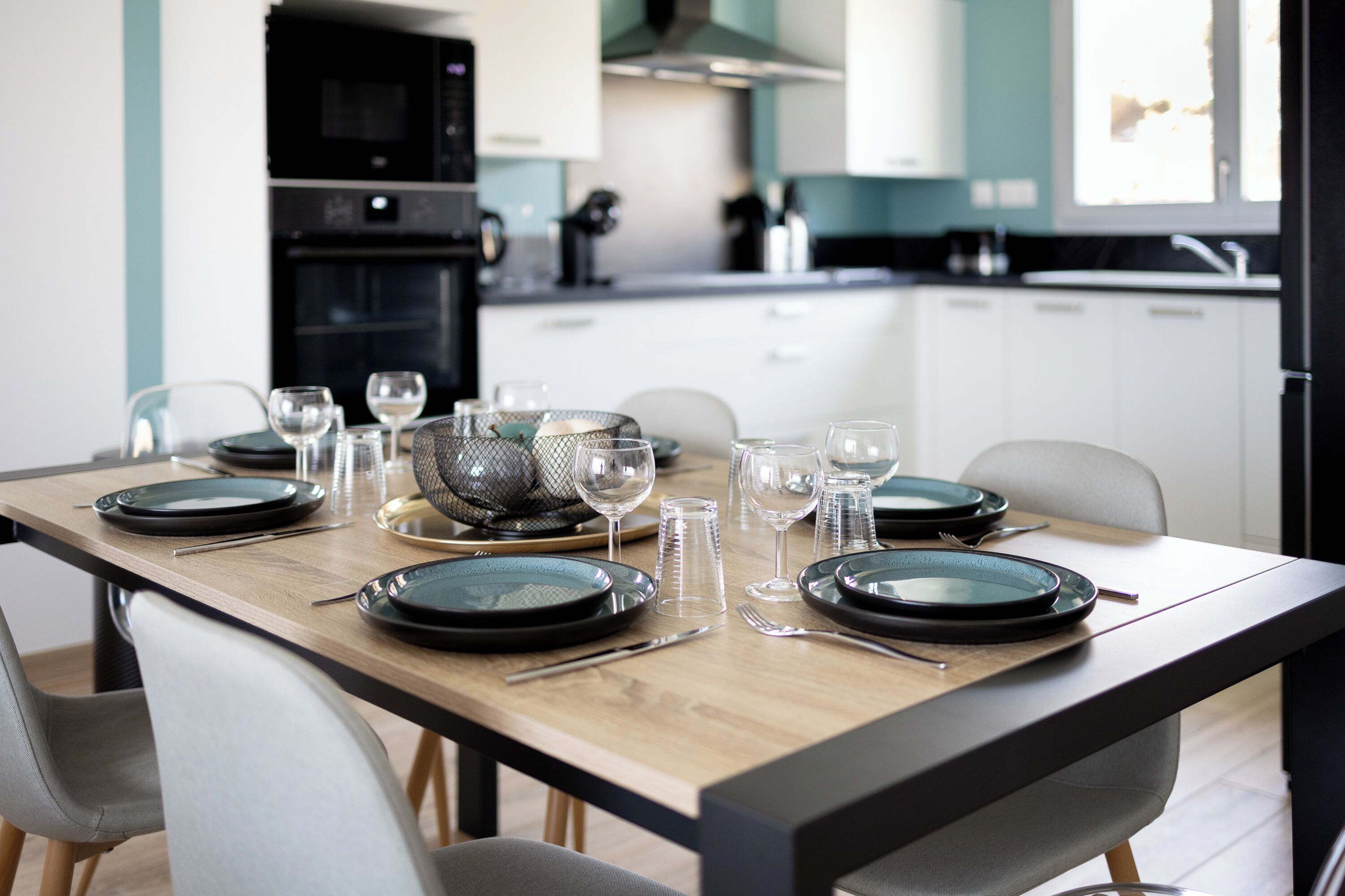 Een moderne keuken met een eettafel voor vier personen, compleet met borden, glazen en bestek.