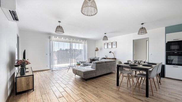 A modern living room with a sofa, dining table, and pendant lights.