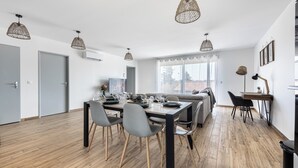 A modern dining area with a wooden table, grey chairs, and hanging pendant lights.