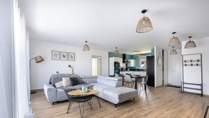 A modern living room with a sectional sofa, a round coffee table, and a dining area with a small table and chairs.