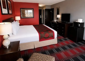 Ein Hotelzimmer mit Bett, Schreibtisch, Stuhl, Fernseher und Mikrowelle.