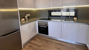 Une cuisine moderne avec des armoires blanches, un réfrigérateur en acier inoxydable, un four encastré et un four à micro-ondes.