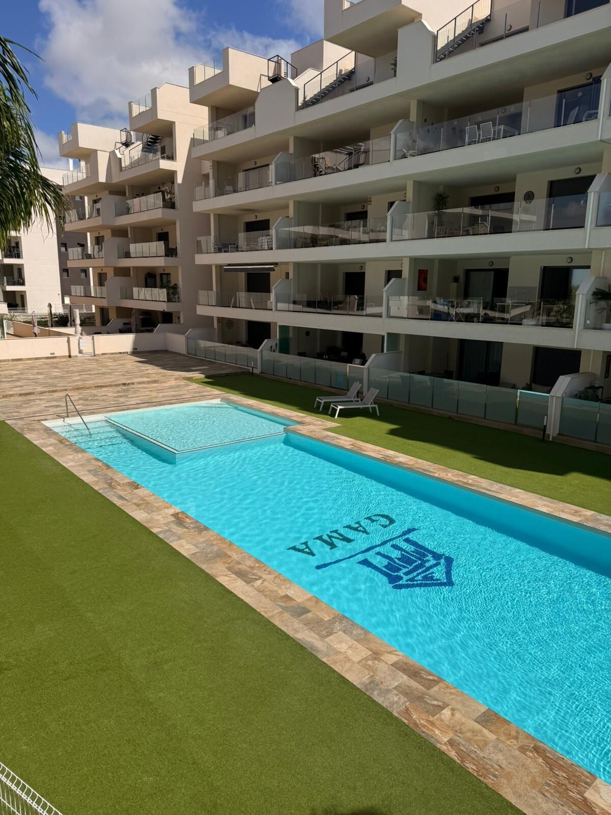 Un hôtel moderne doté d’une piscine, de nombreux balcons et d’une pelouse bien entretenue.