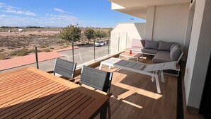Une terrasse extérieure moderne, avec une table et des chaises en bois, un canapé et une vue sur le paysage.