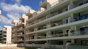 Un hôtel moderne à plusieurs étages, doté d’une piscine, d’un espace extérieur aménagé et de balcons.
