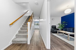 A modern interior with a wooden staircase, a blue accent wall, and a seating area with a plant. - 4 Bed House Close To Gatwick Free Parking (West Sussex)