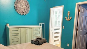 Ein Schlafzimmer mit Bett, Schminktisch, einer Tür und einer Wanddekoration.