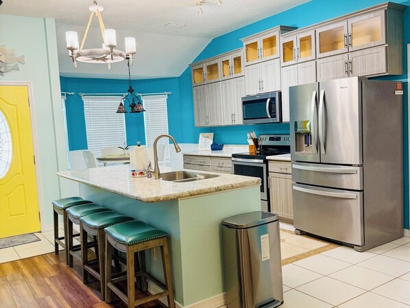 A kitchen with a central island, stainless steel appliances, and a blue accent wall.