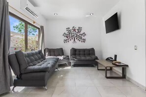 Ein modernes Wohnzimmer mit zwei grauen Sofas, einem Couchtisch und einem an der Wand montierten Fernseher.