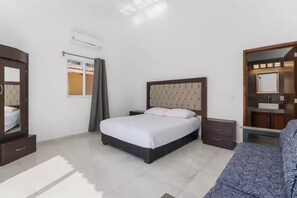 Een slaapkamer met een bed, een kledingkast, een spiegel, een nachtkastje en een poster aan de muur.