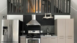 Una cocina moderna con refrigerador, horno y estufa de acero inoxidable, un salpicadero negro y un armario gris.