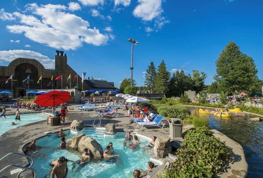 A swimming pool area with lounge chairs, a water slide, and a large building with a distinctive arch in the background.